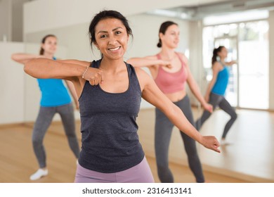 Young adult colombian woman dancing during group class in dance center