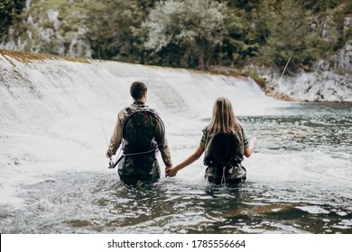 Young Adult Couple Is Fishing Together On Fast Mountain River. Active People And Sport Fly Fishing Concept.