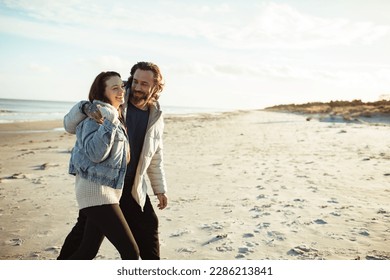 Young adult couple walking on a beach during cold weather - Powered by Shutterstock