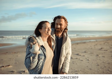 Young adult couple walking on a beach during cold weather - Powered by Shutterstock