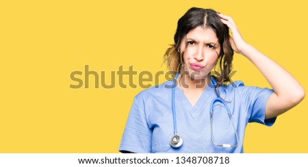 Young adult doctor woman wearing medical uniform confuse and wonder about question. Uncertain with doubt, thinking with hand on head. Pensive concept.