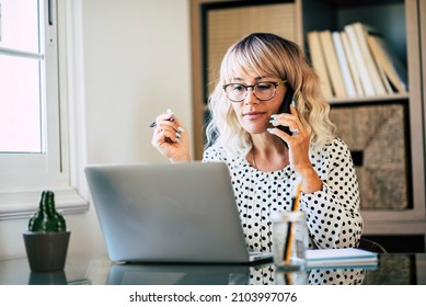 Young Adult Entreprenaur Woman Working At Office With Laptop Computer And Mobile Phone Cell Connection - Professional Business Lady With Eyewear Busy In Smart Working At Home - Modern People Online