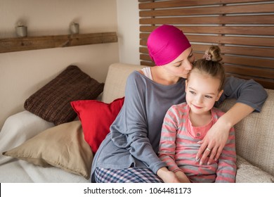 Young Adult Female Cancer Patient Spending Time With Her Daughter At Home, Relaxing On The Couch. Cancer And Family Support Concept.