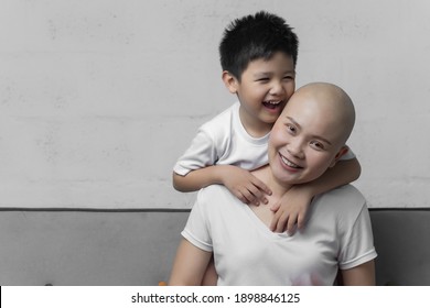 Young Adult Female Cancer Patient Spending Time With Son At Home, Relaxing On The Couch. Cancer And Family Support Concept.