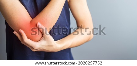 Young adult female with her muscle pain on gray background. Woman having elbow ache due to lateral epicondylitis or tennis elbow. injuries and medical concept