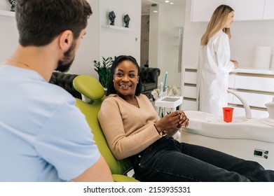 Young Adult Female Patient Sitting On A Dental Chair And Having A Conversation With Her Dentist. Preparing Patient For A Treatment. Patient Smiling.