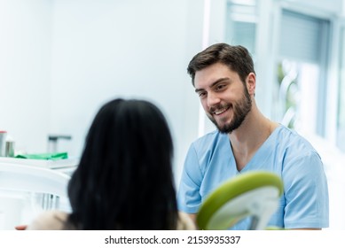 Young Adult Female Patient Sitting On A Dental Chair And Having A Conversation With Her Dentist. Preparing Patient For A Treatment. Rear View Of The Patient, Focus On A Dentist.