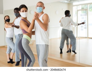 Young Adult Females And Males In Masks For Disease Prevention Doing Samba Partner Dance Workout During Group Class In Fitness Center