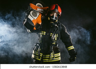 Young Adult Firefighter Saving People From Fire Wearing Uniform And Helmet, Holding Fire Fighting Equipment