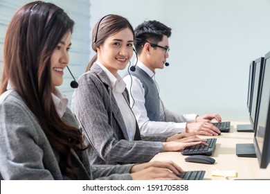 Young adult friendly and confidence operator woman agent smiling with headsets working in a call center with her colleague team working as customer service and technical support workplace.  - Shutterstock ID 1591705858