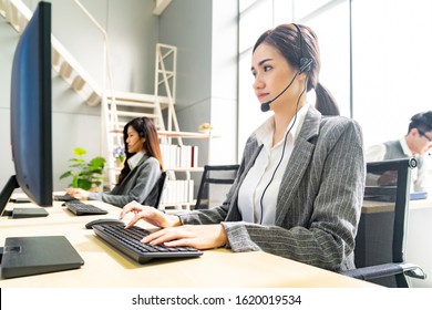 Young Adult Friendly And Confidence Operator Woman Agent Smiling With Headsets Working In A Call Center With Her Colleague Team Working Customer Service And Technical Support Workplace In Background.