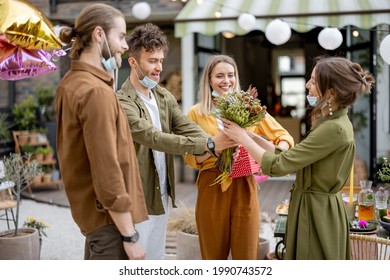 Young Adult Friends Gathering For Birthday Party At The Backyard Of Country House. Wearing Face Masks And Greet With Social Distance, New Normal During Pandemic