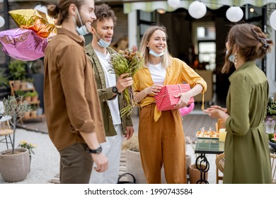 Young Adult Friends Gathering For Birthday Party At The Backyard Of Country House. Wearing Face Masks And Greet With Social Distance, New Normal During Pandemic