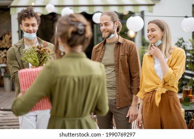 Young Adult Friends Gathering For Birthday Party At The Backyard Of Country House. Wearing Face Masks And Greet With Social Distance, New Normal During Pandemic