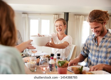 Young Adult Friends Passing Food Across During Lunch At A Dinner Table, Close Up