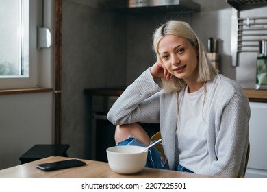 young adult generation z woman sits in her kitchen and looking at camera - Shutterstock ID 2207225501