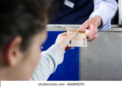 Young adult girl paying toll on highway at the tollbooth. Selective focus on the hands.