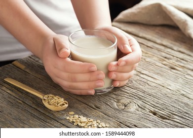 Young Adult Hands Holds Drinking Glass With  Organic Oat Milk . Healthy Eating Lactose Free Milk Substitute Concept .Close Up,selective Focus.