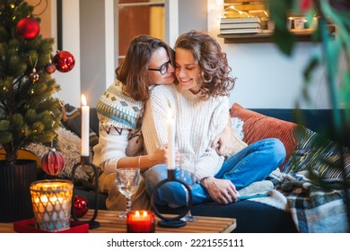 Young adult happy lesbian couple sitting on couch at home hugging and celebrating christmas and new year eve - Powered by Shutterstock