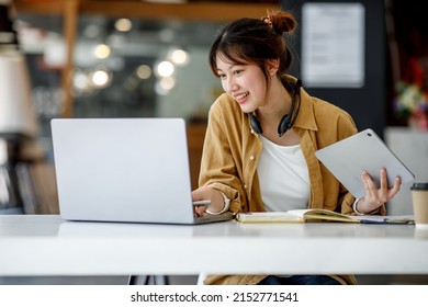 Young Adult Happy Smiling Hispanic Asian Student Wearing Headphones Talking On Online Chat Meeting Using Laptop In University Campus Or At Virtual Office. College Female Student Learning Remotely.