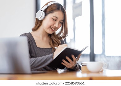 Young adult happy smiling Hispanic Asian student wearing headphones Online education using laptop in university campus or at virtual office. College female student learning remotely. - Shutterstock ID 2258593661