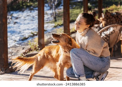 Young adult happy woman playing with her retriever dog on the terrace of a country house i