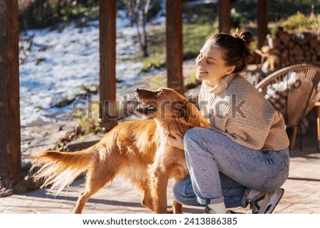 Young adult happy woman playing with her retriever dog on the terrace of a country house i