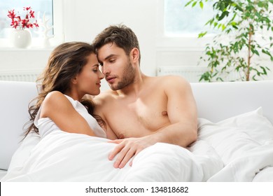 Young Adult Heterosexual Couple Lying On Bed In Bedroom