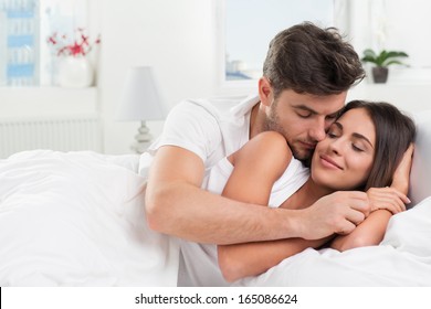 Young Adult Heterosexual Couple Lying On Bed In Bedroom