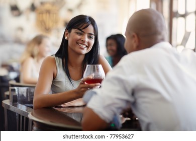young adult hispanic couple dining out in restaurant and toasting with cocktails. Horizontal shape, front view, focus on background