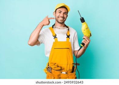 young adult hispanic man smiling confidently pointing to own broad smile. worker and drill concept - Powered by Shutterstock