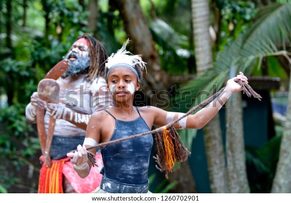 Young adult Indigenous Australian Aboriginal woman\
dancing to the singing rhythm sound of Australian Aboriginal adult\
man in the tropical far north of Queensland, Australia.Real people.\
Copy space