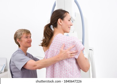 A young adult lady being helped and attended by a middle aged radiologist on a mammogram machine