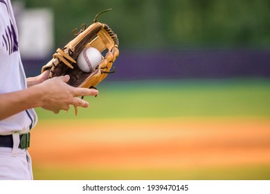 A Young Adult Male Baseball Player Holding A Baseball Glove And Baseball Ball In His Glove.