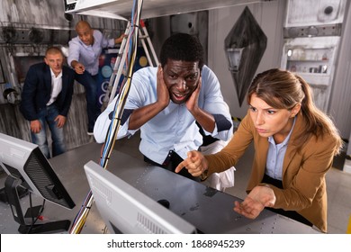 Young Adult Male And Female Colleagues Trying To Solve Conundrum Using Computer To Get Out Of Escape Room During Corporate Event