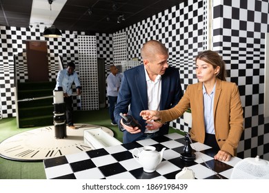 Young Adult Male And Female Colleagues Trying To Solve Puzzle To Get Out Of Escape Room During Corporate Event