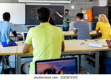 Young Adult Male Lecturer Teaching During Technology Class. Multiracial Young Students Listening Teacher In Classroom