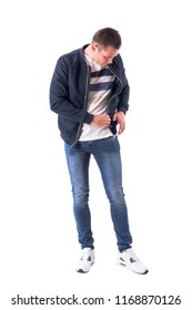 Young Adult Man In Bomber Jacket Searching For Something Lost In The Pocket. Full Body Isolated On White Background.