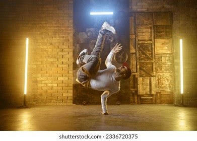 Young adult man breakdancing doing one handed handstand