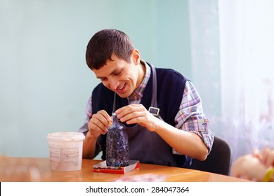 Young Adult Man With Disability Engaged In Craftsmanship On Practical Lesson, In Rehabilitation Center