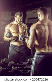 Young Adult Man Doing Bicep Curls In Modern Gym.