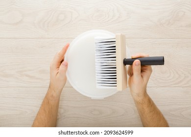 Young Adult Man Hands Holding Brush And Bucket With Glue On Light Wooden Table Background. Ready To Glue Wallpaper. Closeup. Point Of View Shot. Preparing For Repair Work Of Home. 