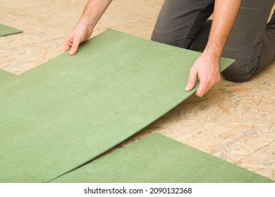 Young adult man hands laying green natural wood fiber insulation board. Preparing surface from fibreboard underlay for laminate or parquet floor. Repair work of home. Renovation process. Closeup. - Shutterstock ID 2090132368