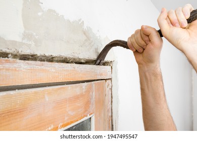 Young Adult Man Hands Using Crowbar And Breaking Old Wooden Door Frame From Wall. Closeup. Preparing For Repair Work Of Home. Side View.