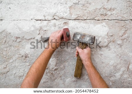 Young adult man hands using sledgehammer, metal stone chisel and removing old concrete on floor. Closeup. Point of view shot. Preparing for repair work of home. Flooring restoration.
