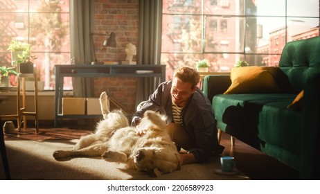 Young Adult Man Having Fun and Playing with His Golden Retriever Pet on a Living Room Floor. Attractive Dog Owner Petting, Scratching and Teasing His Canine Best Friend at Home. - Powered by Shutterstock