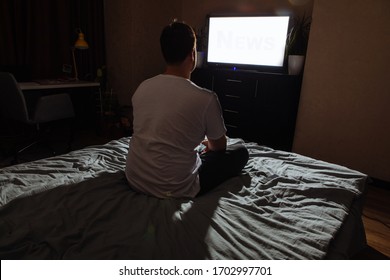 Young Adult Man Sitting On Bed Looking TV