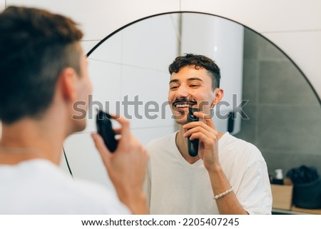 young adult man trimming hos mustaches in bathroom
