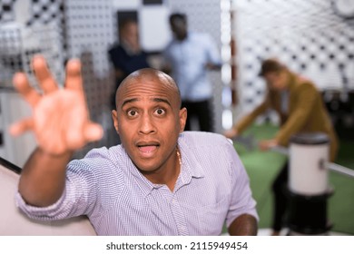 Young Adult Man Trying To Solve Puzzles To Get Out Of Escape Room, Reaching For Next Key