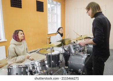Young adult men and women learn to play drums at school. Hobbies and pastime. Art and life style.